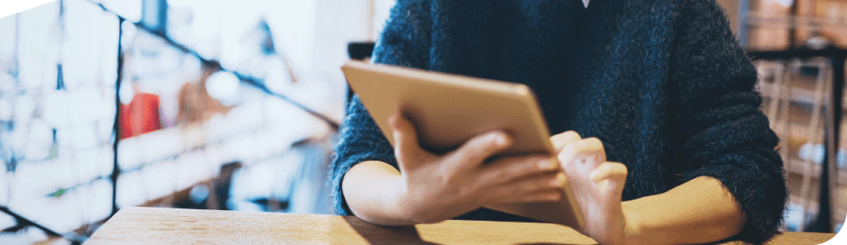 Person, die ein Tablet nutzt, um Immobilien-Investments zu recherchieren.